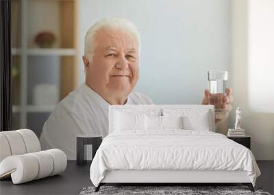 Positive senior man keeps healthy preventing dehydration by drinking enough water Wall mural