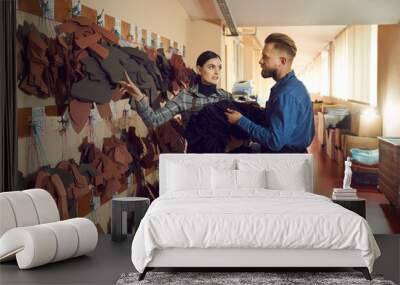 Shoe production, footwear manufactory concept. Two young male and female shoemaker colleague discussing and choosing leather material for handmade boots design. Master teaching student Wall mural