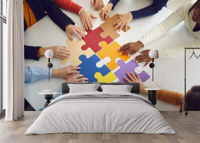 Solidarity, strategy collaboration, business workflow and communication research concept. Diverse multiethnic office people team assembling jigsaw puzzle pieces holding hands on table top view Wall mural