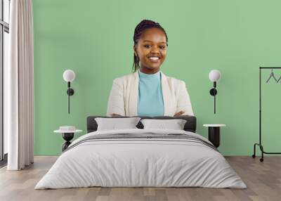 Studio portrait of black businesswoman with toothy smile. Confident good looking young woman with Afro braids, in white jacket and mint turtleneck standing isolated on solid green colour background Wall mural