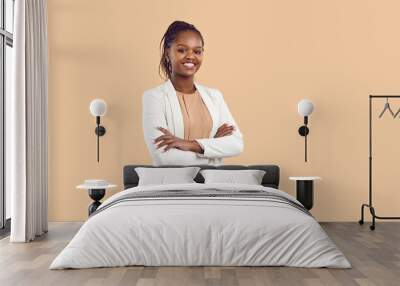 Studio portrait of happy successful confident black business woman. Beautiful young lady in white jacket smiling at camera standing isolated on blank solid beige colour copyspace background Wall mural