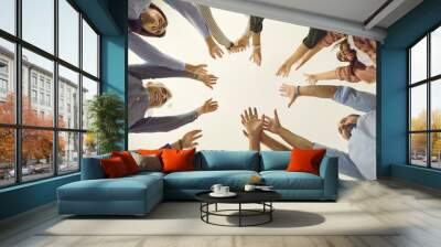 Team of business people reaching up together. Group of young and mature people joining hands, white background, cropped low angle shot, from below bottom view close up. Teamwork, participation concept Wall mural