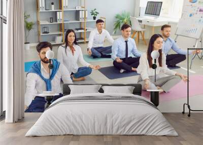 Team of corporate employees having a yoga and meditation break at work in the office. Group of calm, relaxed people meditating for both physical and mental wellness, productivity and good teamwork Wall mural