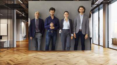 Team of happy satisfied business people standing leaning on grey concrete wall. Banner with group portrait of successful stylish business professionals, entrepreneurs, colleagues, company coworkers Wall mural