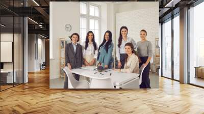 Team of happy successful young business women in their 20s and 30s smiling at camera. Group portrait of female company employees or business partners gathered together in office for work meeting Wall mural