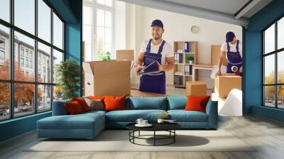 Team of two young male workers from a moving company and removal service packing stuff in cardboard boxes to transport things from one office to another Wall mural