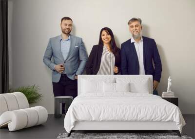 Team of young and mature business people at work. Group portrait of happy colleagues in office. Men and woman wearing smart casual clothes standing by white office wall, smiling, and looking at camera Wall mural