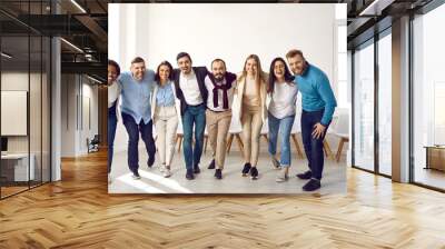 Team of young and successful multiracial people hug and smile at camera together. Portrait of happy smart and modern people in casual clothes standing in row, hugging and laughing. Team unity concept. Wall mural