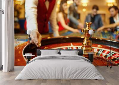 The croupier holds a roulette ball in a casino in his hand. Wall mural