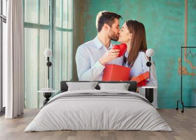 The guy gives a gift box to his girlfriend. Young couple on holiday. St. Valentine's Day. Wall mural