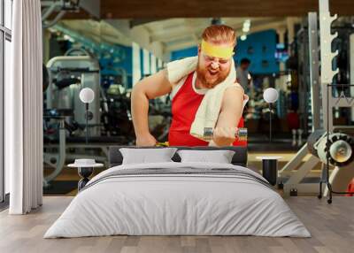 Thick man doing exercises with a barbell in the gym. Wall mural