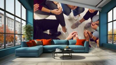 Top view of diverse people sitting in a close circle and talking to a therapist. Cropped image of unidentified people receive help and support during a group therapy session. Concept of group therapy. Wall mural