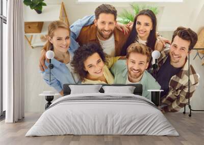 Top view portrait of a group of young happy smiling friends students or colleagues in casual clothes standing together at home and looking up confidently and positively at the camera. Wall mural