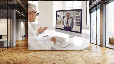 Two happy business people discussing work in virtual online meeting. Senior male executive manager or recruiter talking to new young female colleague or job seeker via video call on modern computer Wall mural