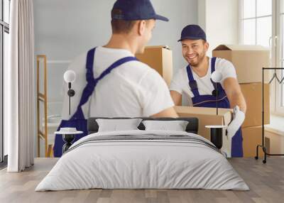 Two skilled man movers, staff of a relocation company, work during a home or office move. With precision and teamwork, they handle cardboard boxes, ensuring the safe delivery of belongings. Wall mural