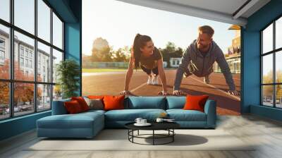 Young couple doing pushups in the stadium Wall mural