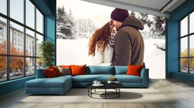 Young couple on the snow in winter in the park Wall mural