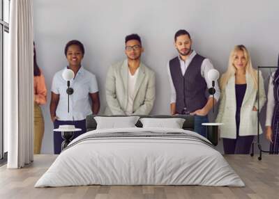 Young diverse fashion models posing against gray background. Banner with group portrait of confident young multi ethnic people in smart casual office wear standing in studio and leaning on grey wall Wall mural