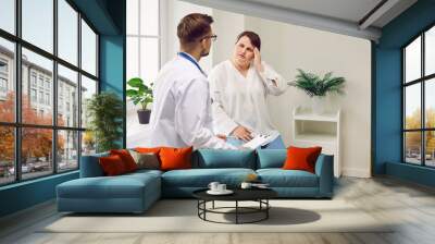 Young fat woman sitting on the couch in the doctor's office suffering from headache feel stressed, migraine or depression during medical examination in clinic. Health care and medicine concept. Wall mural