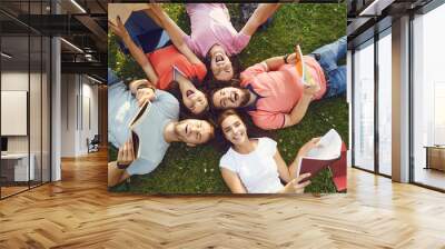 Young people are laughing while lying on the grass Wall mural