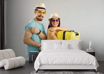 Young people ready for safe summer holiday journey. Studio portrait of happy couple holding travel cases, smiling and showing arms after receiving COVID-19 vaccine. Coronavirus vaccination concept Wall mural