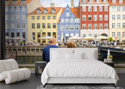 Tourists enjoying the scenic summer view of Nyhavn pier. Colorful building facades with boats and yachts in the Old Town of Copenhagen, Denmark Wall mural