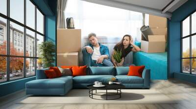 young couple man and woman looking tired sitting on the floor during moving to new appartment unpacking boxes, , moving process Wall mural