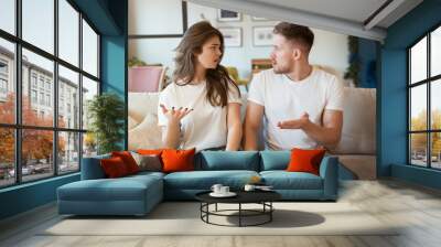 young couple man and woman sitting on the sofa both looking irritated, grimacing mood Wall mural