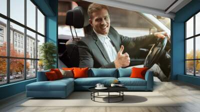 young handsome businessman driving luxury car looking satisfied, showing like sign, successful strategy concept Wall mural