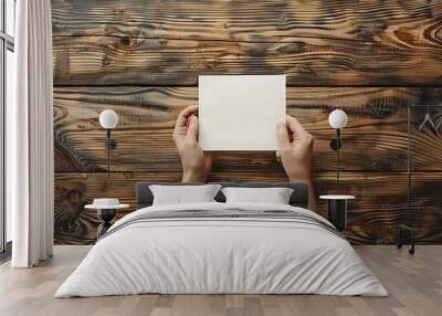 A woman hand places a note on the clean wood table bird view Wall mural