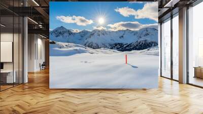 Snowy mountain range with a bright sun shining through the clouds. Wall mural