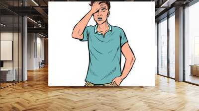 A young man holds his hand to his head. Headache Wall mural