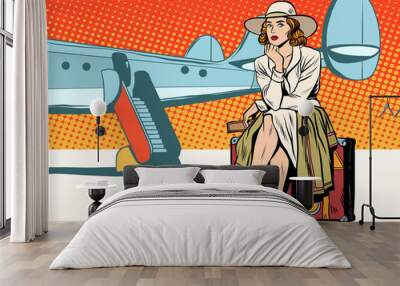 Tourist girl sitting on a suitcase, travelling by plane Wall mural