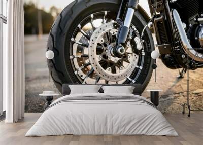 Close-up of a motorcycle front wheel featuring a detailed view of the suspension, brake disc, and tire on an asphalt surface. Wall mural