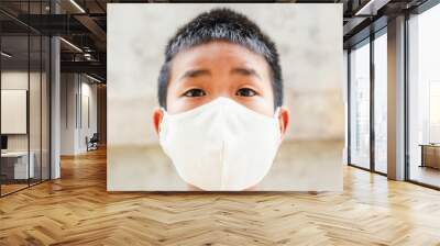 Asian children boy wear N95 mask to protect PM 2.5 dust and air pollution.Children boy in city street wearing face mask protective for spreading of disease Coronavirus. Wall mural