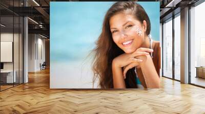 Beautiful happy Girl applying Sun Tan Cream on her Face Wall mural