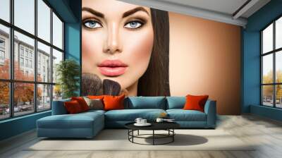 Beauty brunette girl with makeup brushes Wall mural