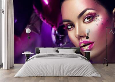 Beauty fashion model girl creative art makeup with gems. Woman face over purple, pink and violet air balloons background Wall mural