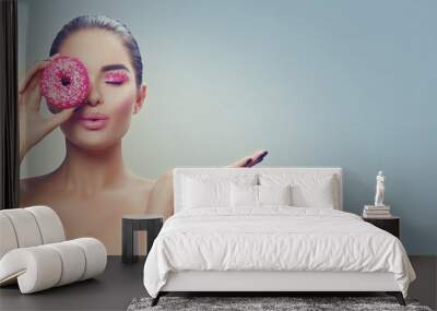 Beauty fashion model girl holding sweet pink donut and pointing hand, showing products Wall mural