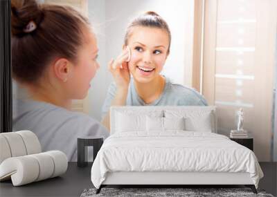 Beauty girl cleaning her face with cotton pad at home Wall mural