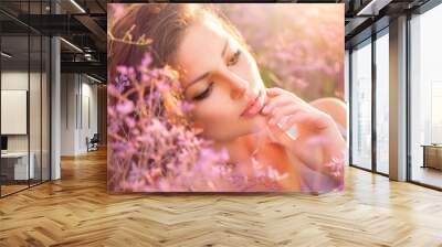 Beauty Girl Lying on a Meadow with Violet Flowers Wall mural