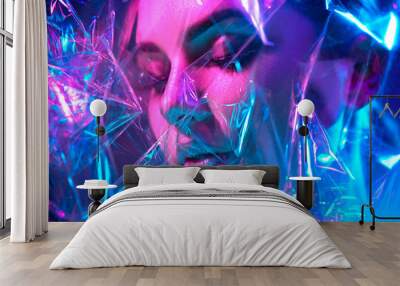 Fashion model woman in colorful bright neon lights posing in studio through transparent film. Portrait of beautiful sexy girl in UV. Art design colorful makeup Wall mural