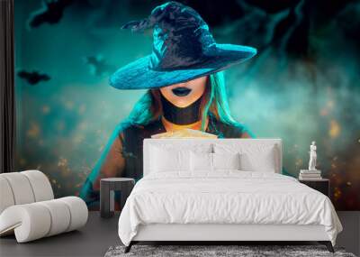 Halloween Witch girl with making witchcraft, magic in her hands, spells. Beautiful young woman in witches hat conjuring. Spooky dark magic forest background. Magician. Wide Halloween party art design Wall mural