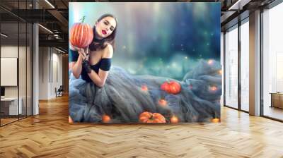 Halloween witch with a carved pumpkin and magic lights in a dark forest Wall mural