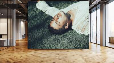 Handsome guy lying on a grass field. Young man enjoying nature outdoors. Young person portrait, fashion guy trendy outdoor photo. Young male fashion art portrait. Handsome brunette Wall mural