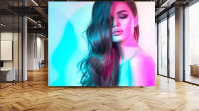 High Fashion model woman in colorful bright neon lights posing in studio, night club. Portrait of beautiful dancer girl in UV. Art design colorful make up. On colourful vivid blue with pink background Wall mural