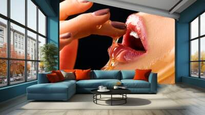 Honey dripping on sexy girl lips. Beauty model woman eating honey. Closeup image Wall mural