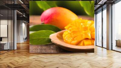 Mango fruit. Ripe Mango fruits on wooden table over nature background. Close-up of fresh juicy tropical mango with leaf, ready to eat healthy sweet dessert, vegan food.  Wall mural