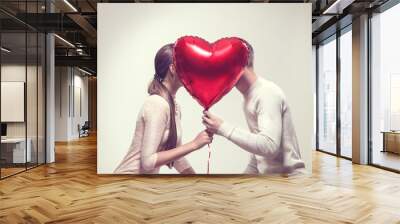 Valentine's day. Happy joyful couple holding heart shaped air balloon and kissing. Love Wall mural