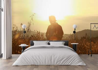 Young man walks in the grain field at sunrise, Background Wall mural